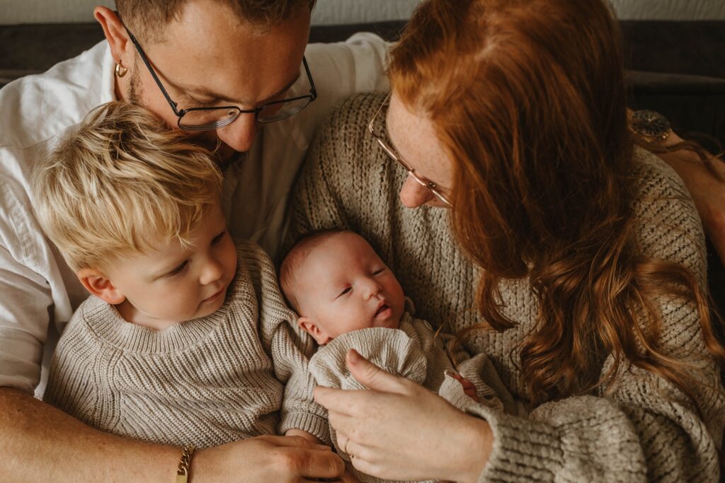 Een close-up van een gezin tijdens de newborn shoot binnen op de bank.