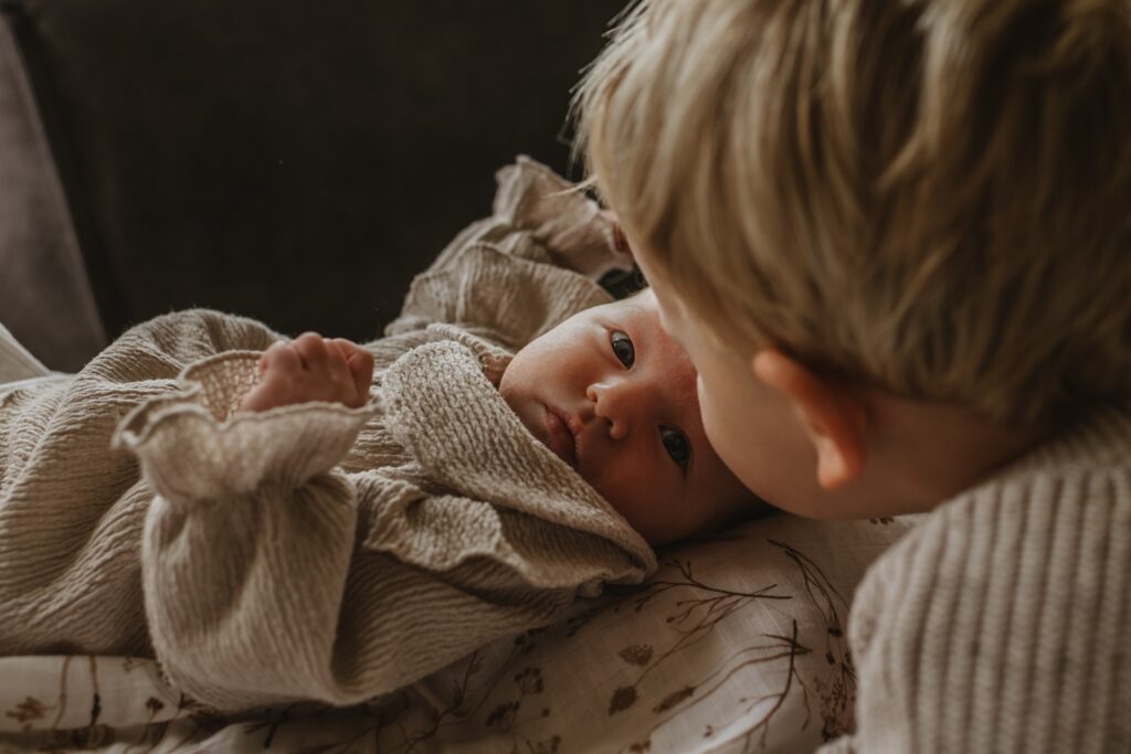 Baby samen met haar oudere broer wanneer de newborn fotoshoot in volle gang is. 